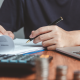 Investor reviewing financial documents and taking notes beside a laptop and calculator for mutual fund investment planning.